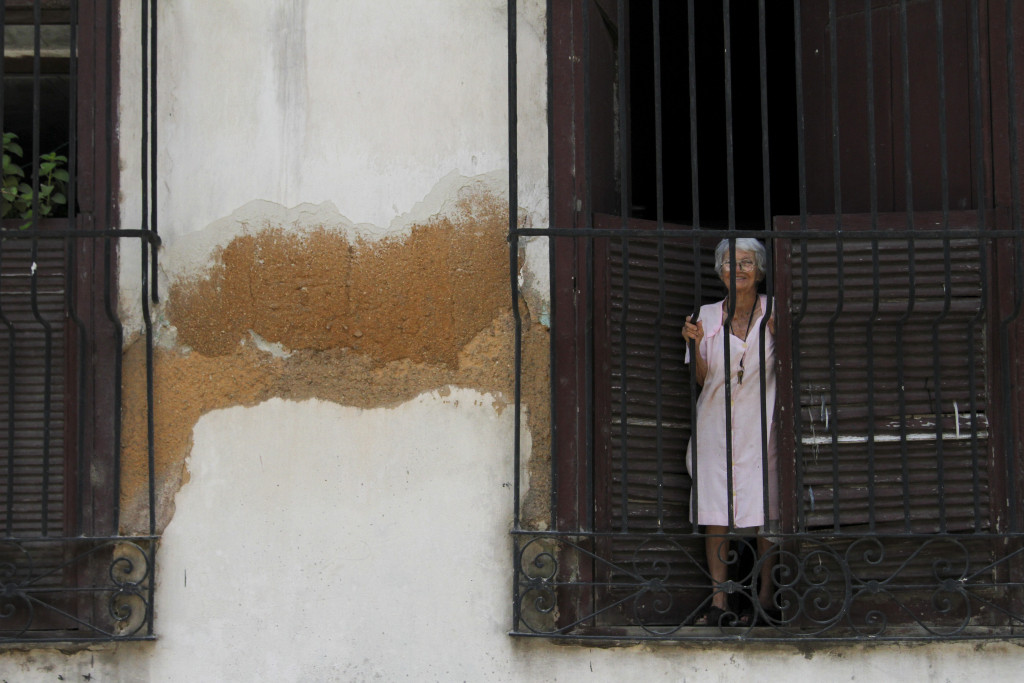 Woman peering out over the streets in Cuba.