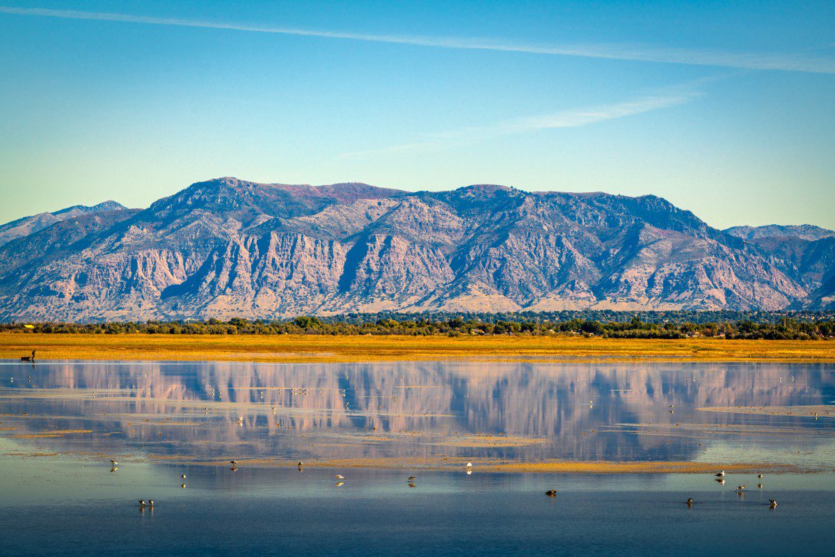 GettyImages-1393996486 Mountain reflected in calm lake under blue sky.