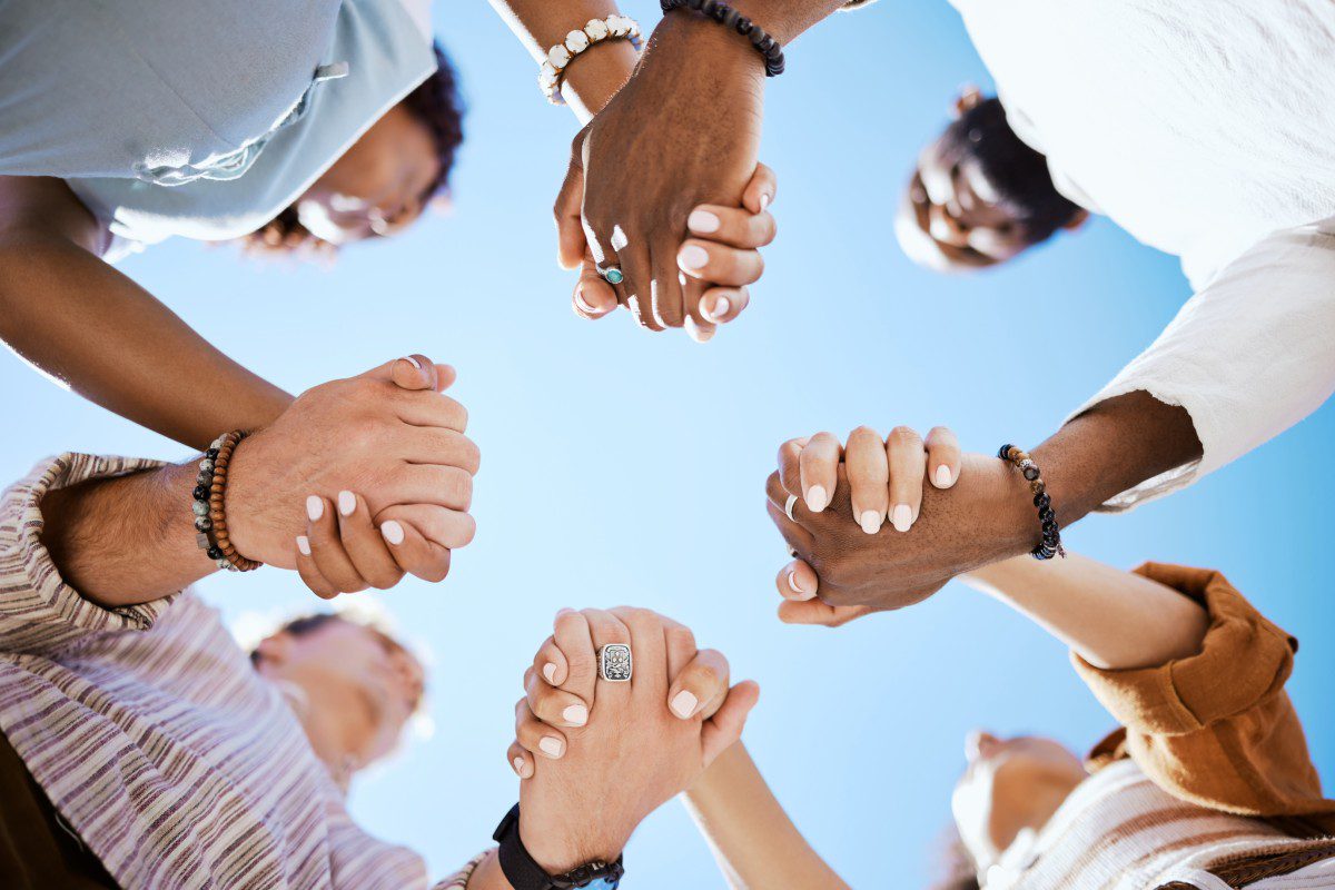 GettyImages-1445245272 Diverse group holding hands in unity.