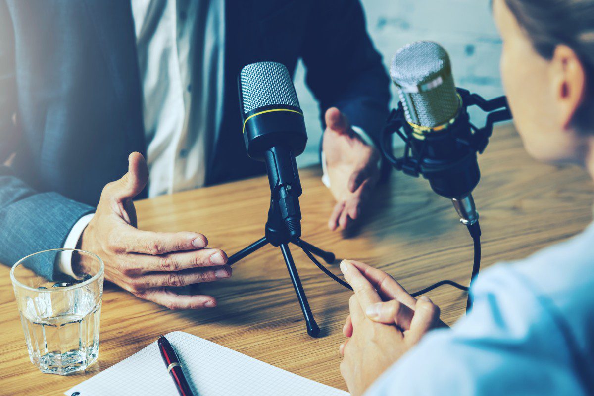 GettyImages-1330934437 Podcast interview with microphones on table.
