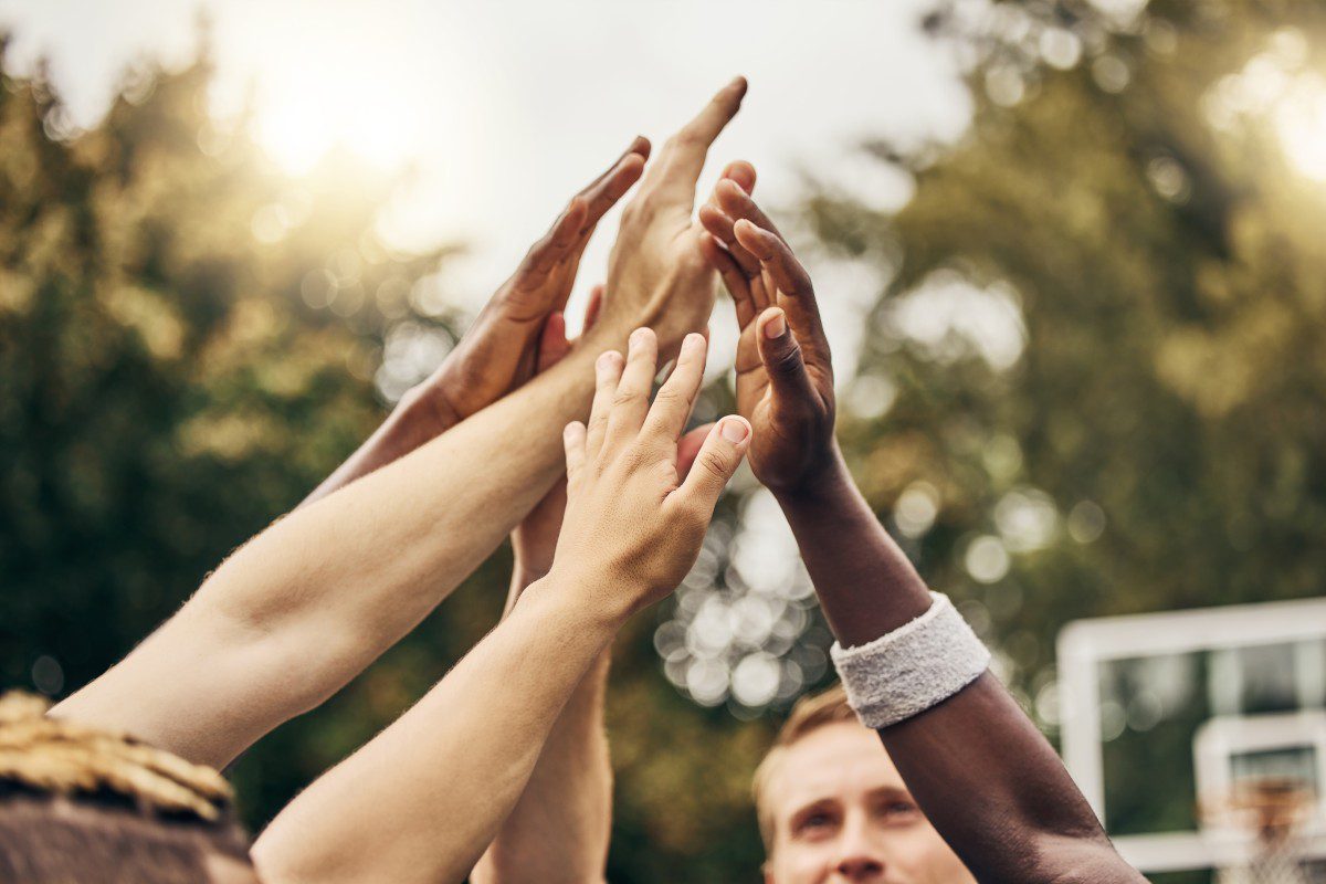 GettyImages-1444399074 Group of hands reaching up outdoors.