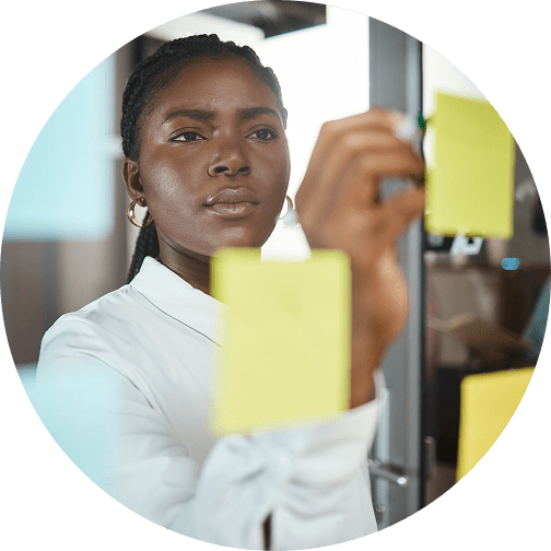GettyImages-1348113184 Woman writing on sticky notes in office.
