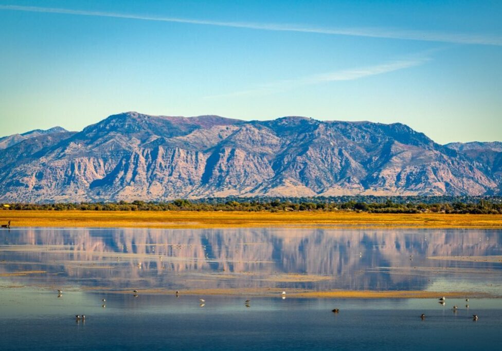 Mountain reflected in calm lake under blue sky.