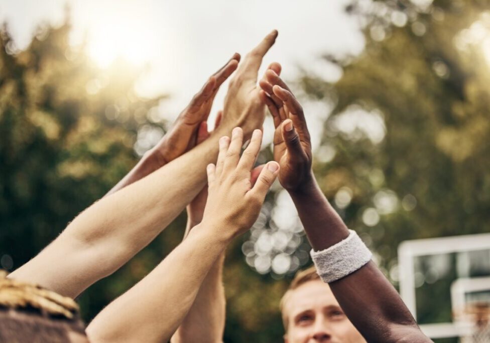 Group of hands reaching up outdoors.