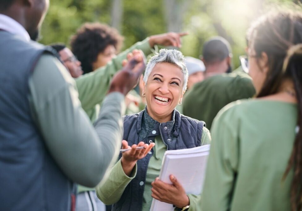 Smiling woman interacting with a group outdoors.