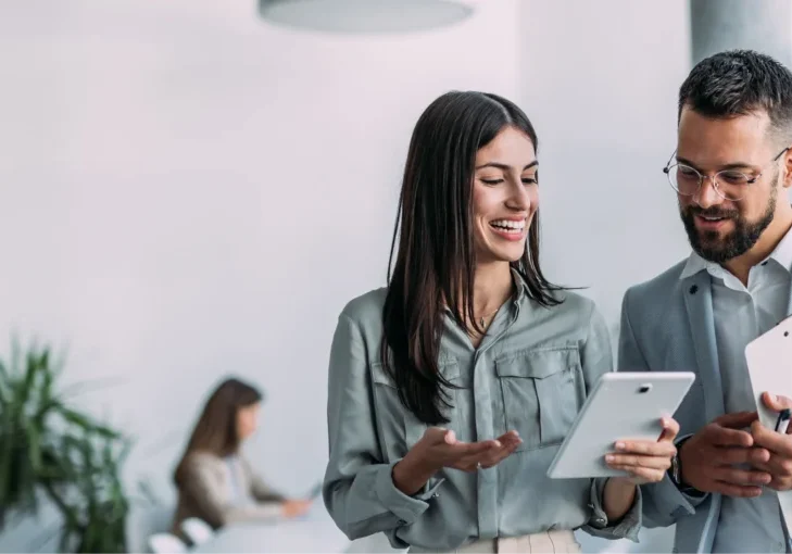 Two colleagues discussing work on tablets.