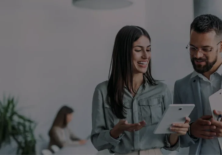 Two colleagues discussing work on tablets.