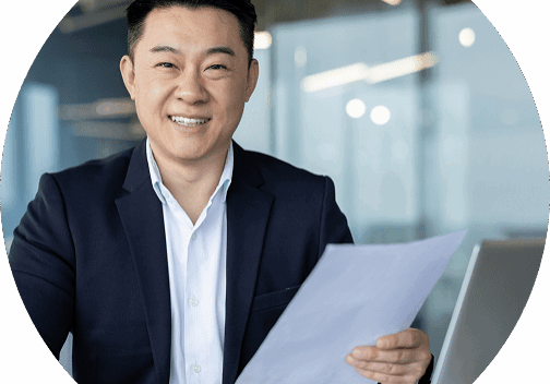 Smiling man holding papers at office desk.